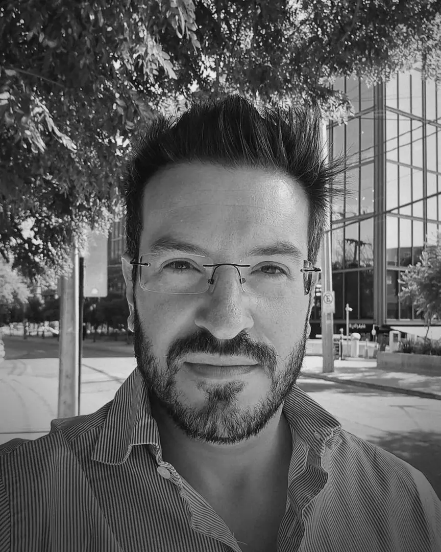 José Racowski al aire libre, frente a un edificio de oficinas.